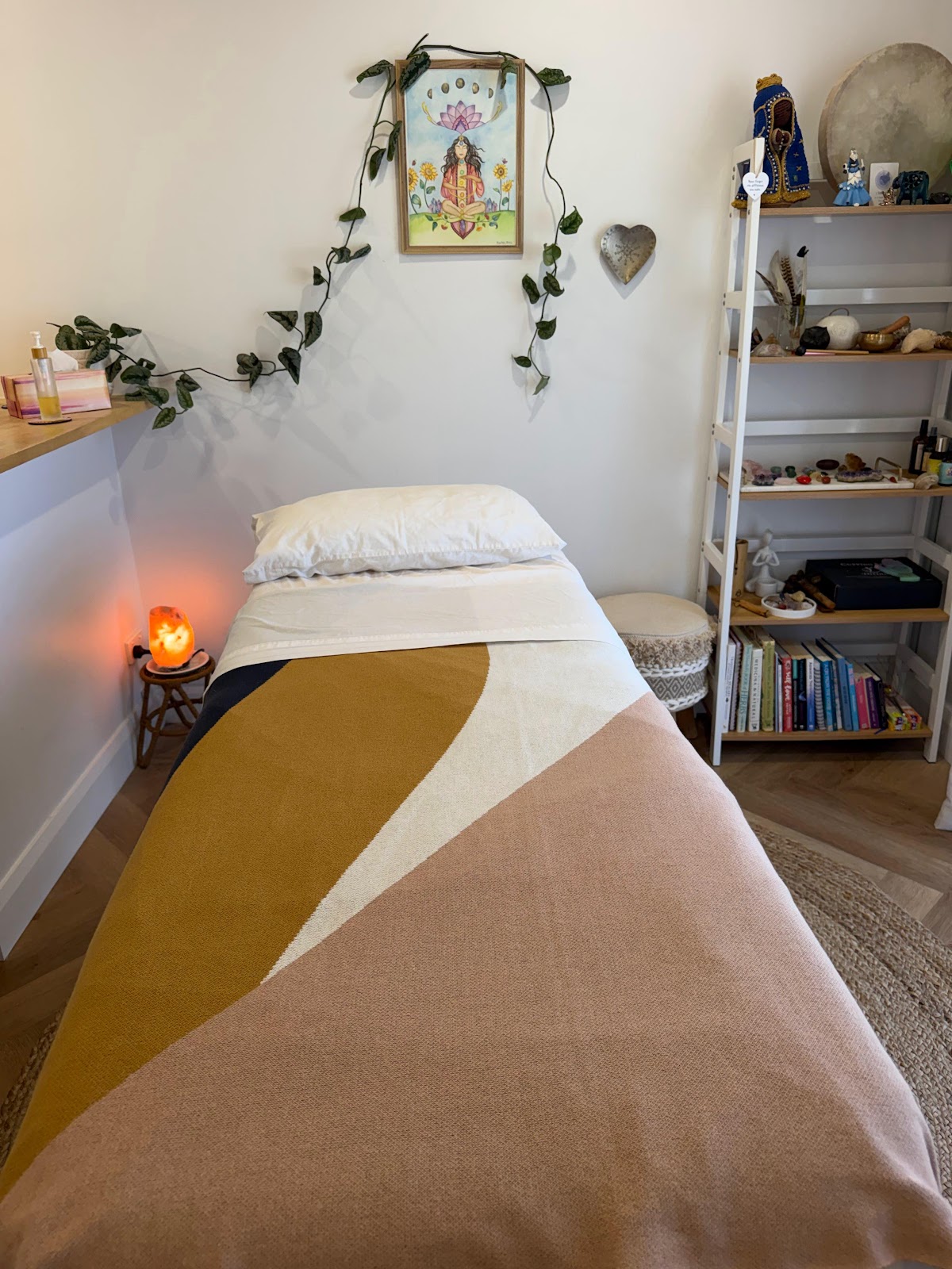 The treatment room at Manipura, a massage table dressed in blush and mustard linen beside a glowing salt lamp