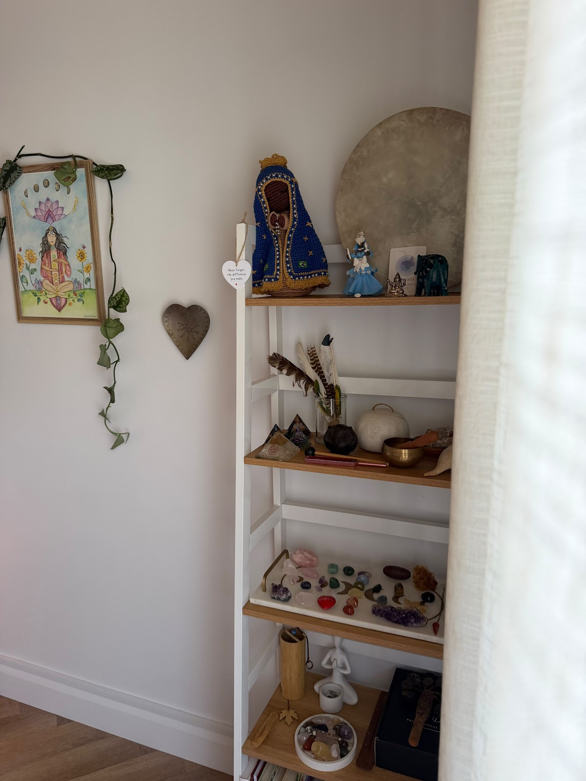 A shelf of crystals, feathers, a frame drum and a singing bowl in the studio