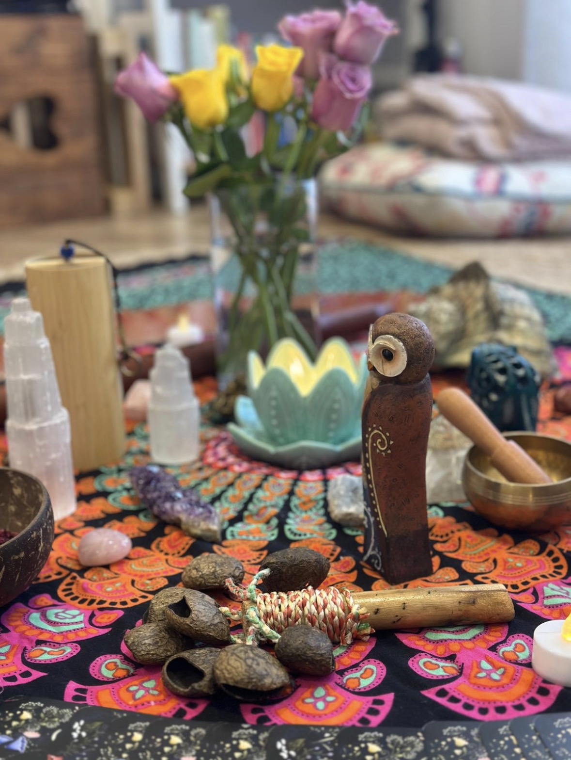 A ceremony altar with roses, selenite, a lotus candle and a singing bowl on a mandala cloth