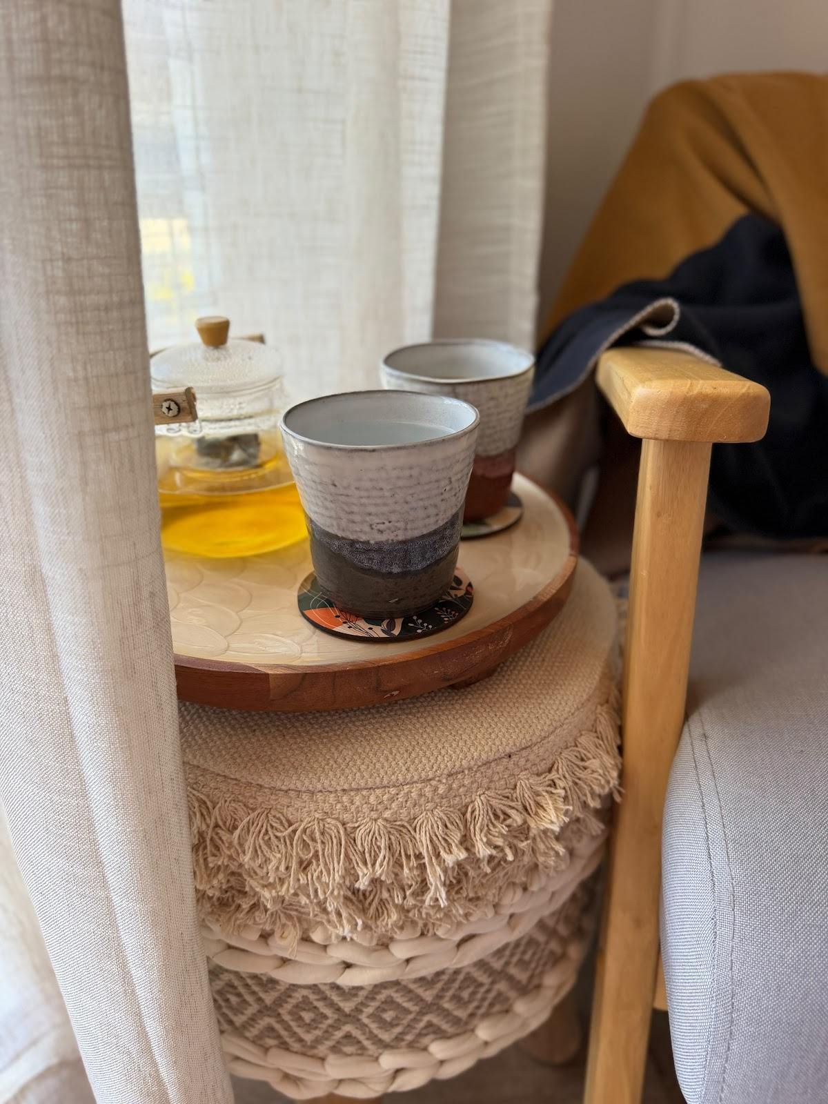 Tea cups and a glass teapot waiting on a side table beside an armchair